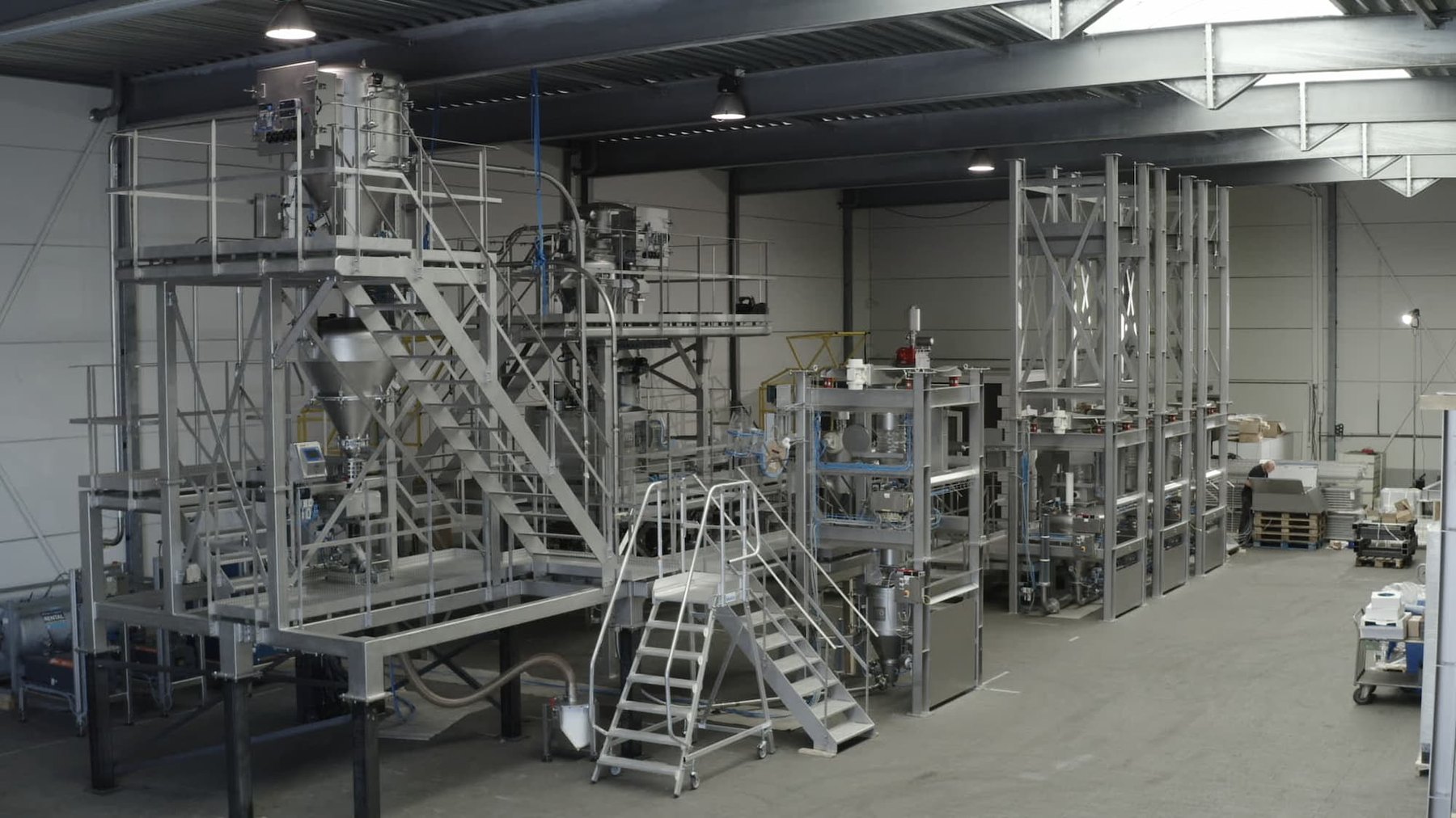 Roestvaststalen procesinstallatie met bordessen, trappen, conische vaten en bigbag-frames, opgebouwd in een testhal in het D-Innocenter van Dinnissen